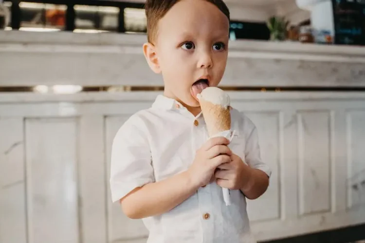 Boy with sensitive teeth eating ice cream in a white shirt