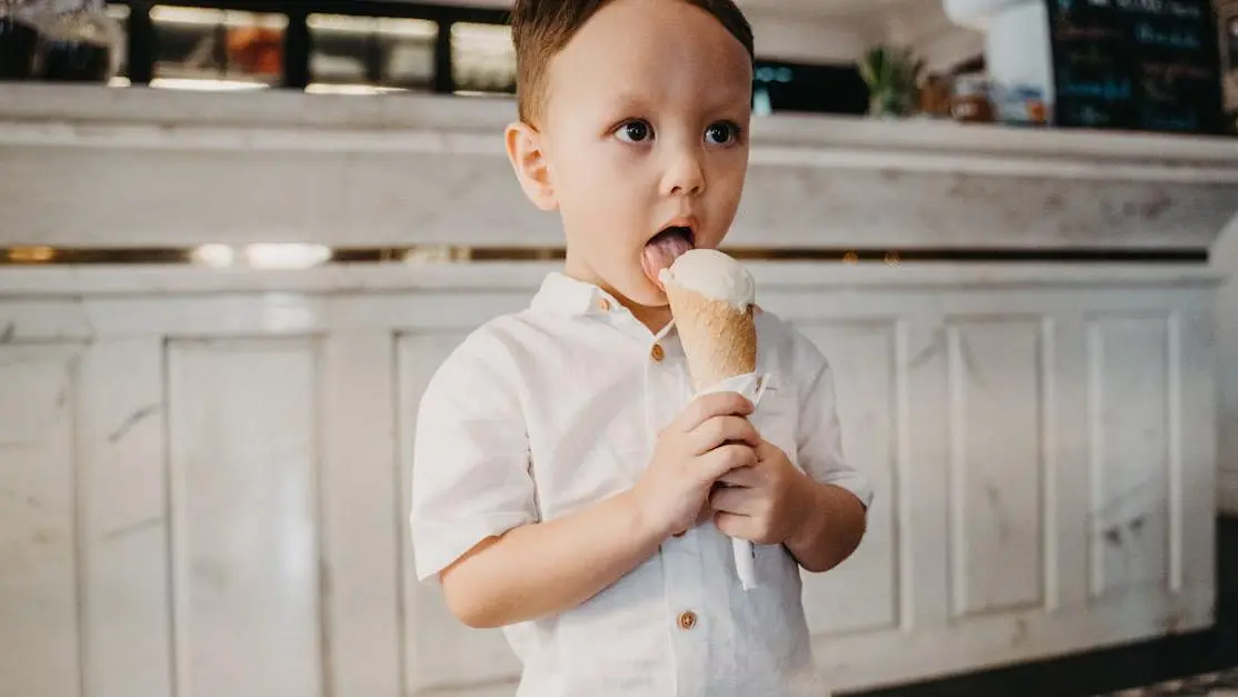 Boy with sensitive teeth eating ice cream in a white shirt