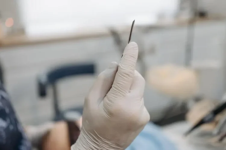 Gloved hands of a specialist preparing dental implants