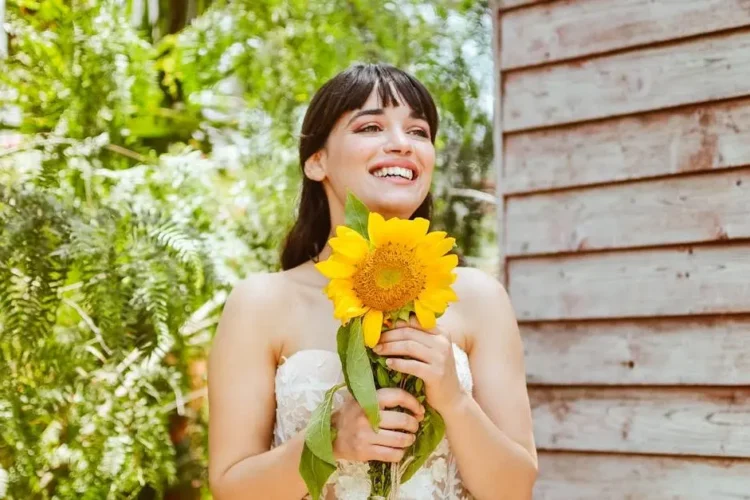 Bride smiling with sunflower, showcasing results of teeth whitening for weddings.