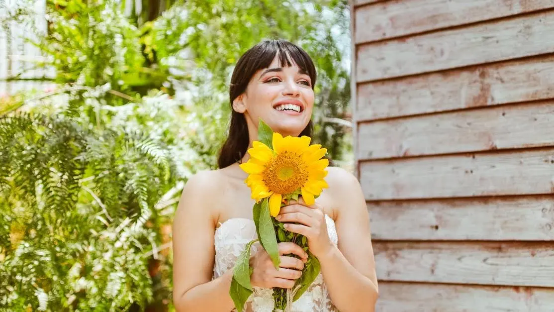 Bride smiling with sunflower, showcasing results of teeth whitening for weddings.