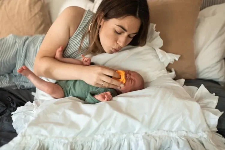 Mother soothing teething baby with pacifier