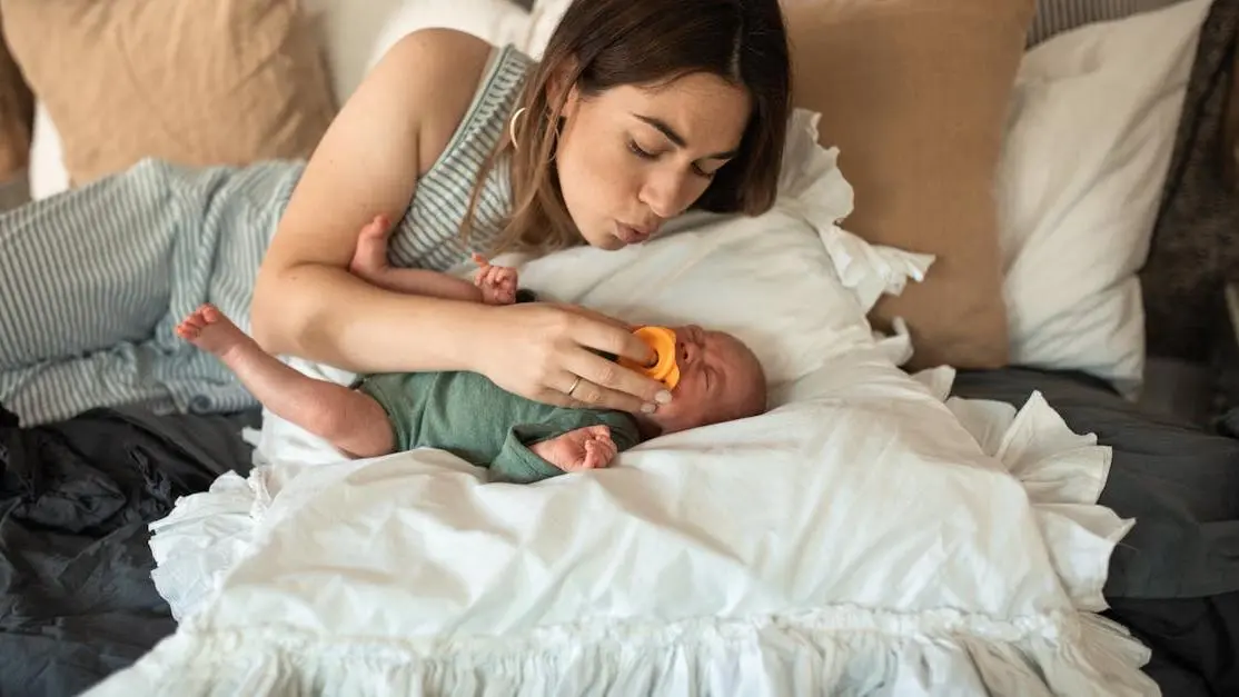 Mother soothing teething baby with pacifier