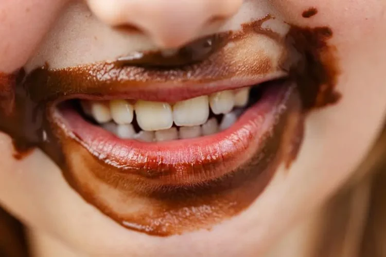 Smiling child with chocolate-stained teeth showing thumb sucking effects on teeth.