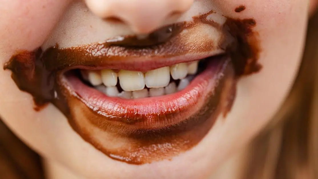 Smiling child with chocolate-stained teeth showing thumb sucking effects on teeth.