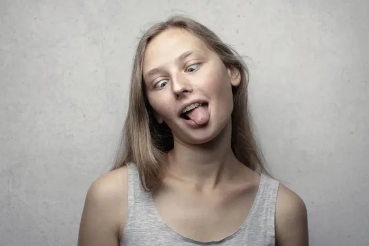 Woman demonstrating tongue thrusting in gray tank top