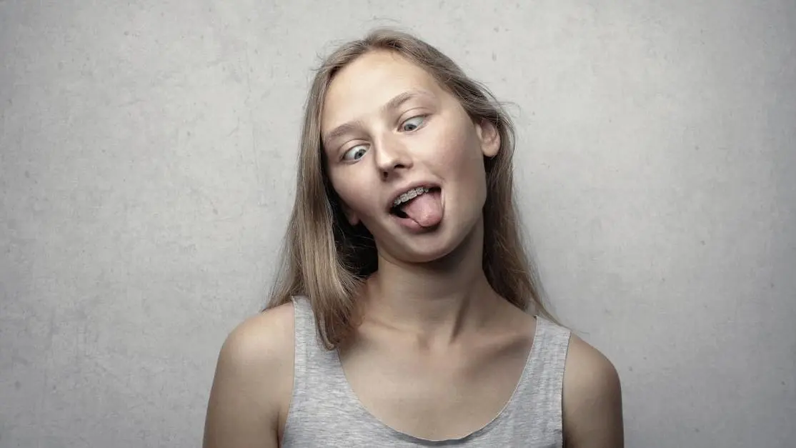 Woman demonstrating tongue thrusting in gray tank top