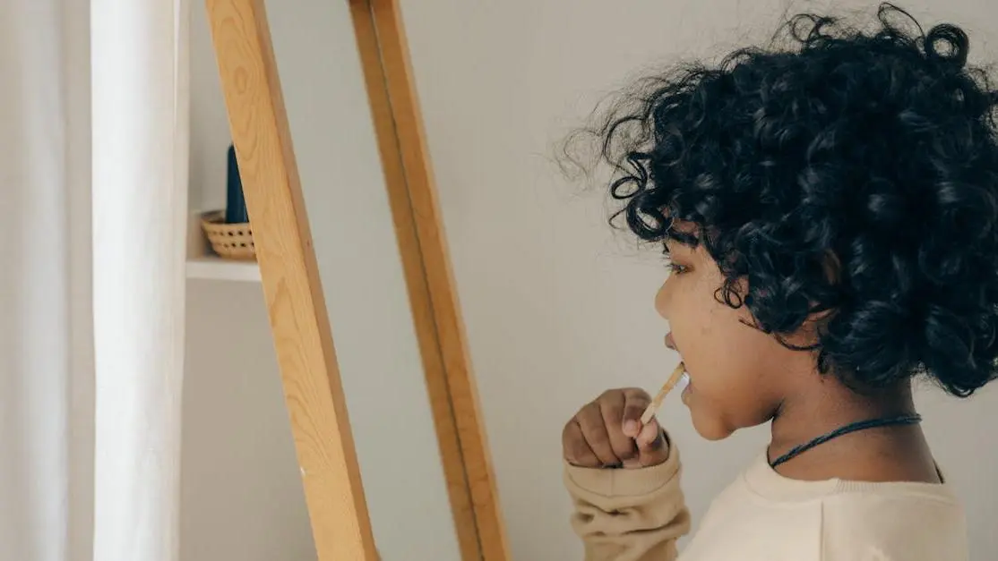 Child brushing teeth in front of mirror to prevent tooth cavities