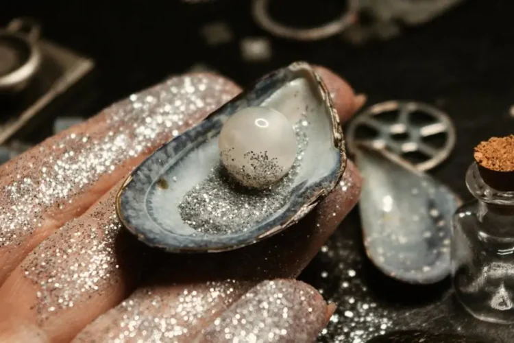 Female hand holding a sparkling pearl in a seashell, illustrating tooth enamel care benefits.