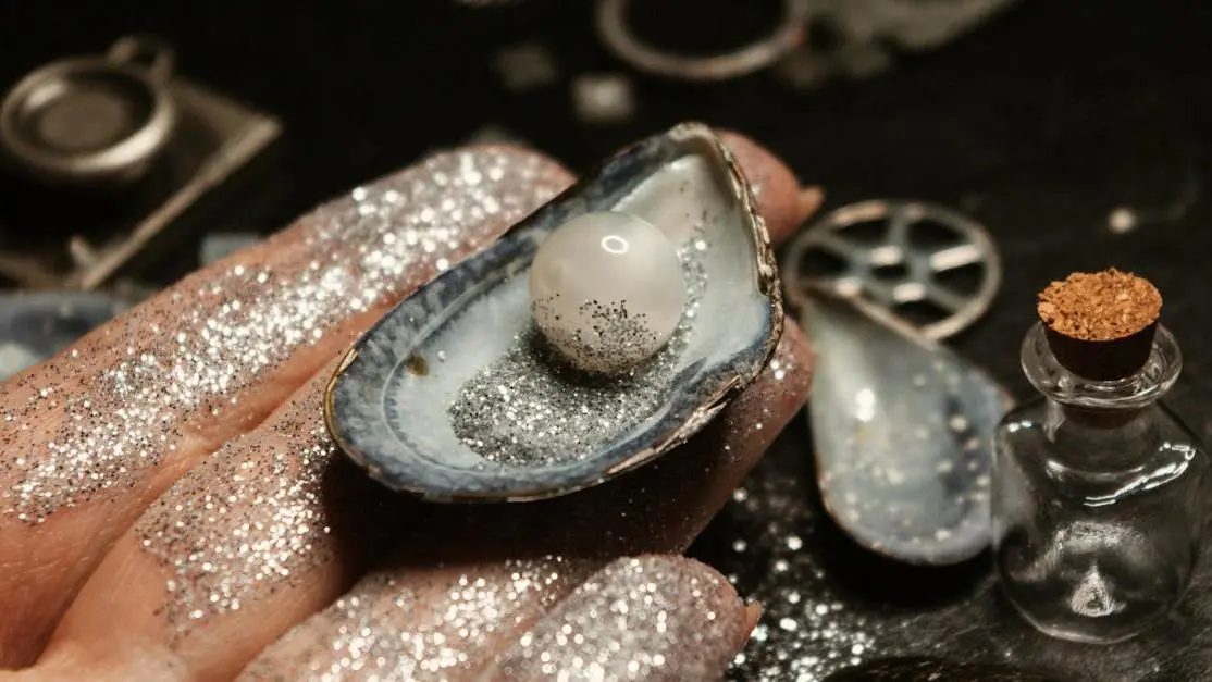 Female hand holding a sparkling pearl in a seashell, illustrating tooth enamel care benefits.