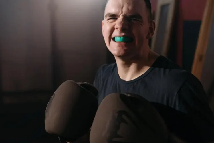 Child wearing boxing gloves with mouthpiece for tooth protection in sports.