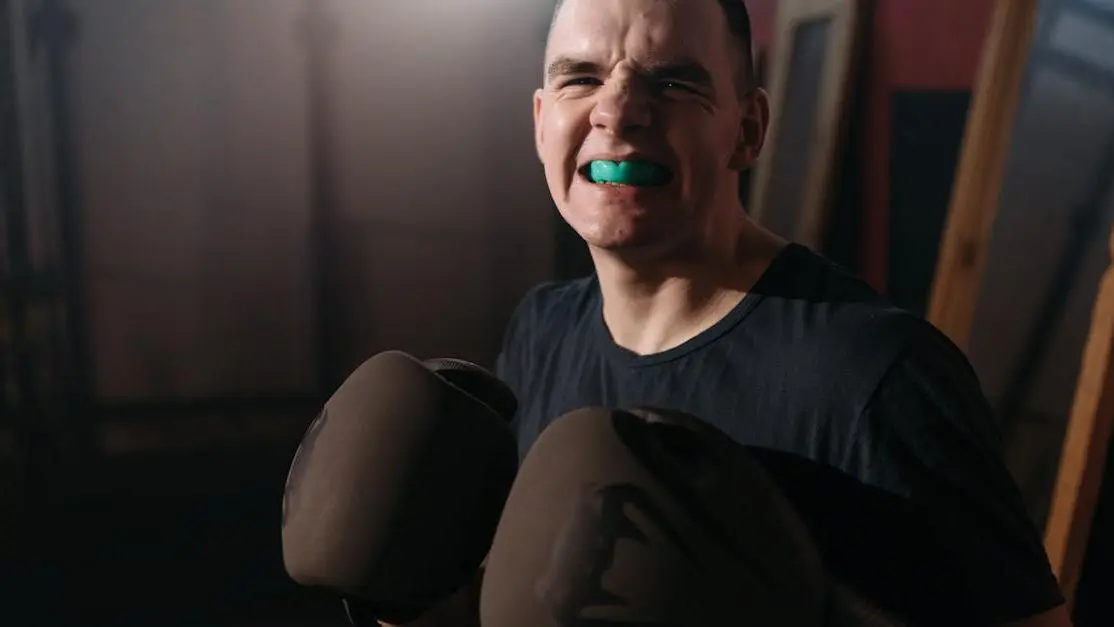 Child wearing boxing gloves with mouthpiece for tooth protection in sports.