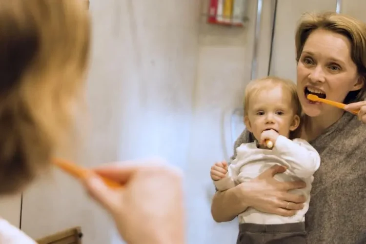 Baby brushing teeth with mother to prevent baby bottle tooth decay.