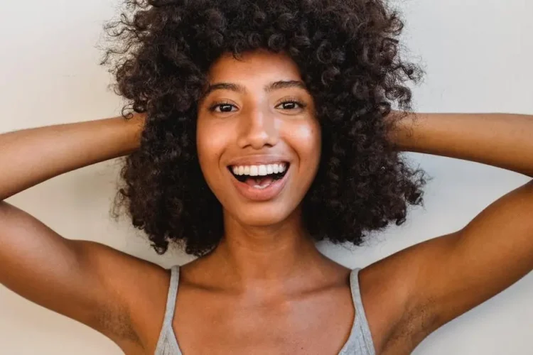 Cheerful African American woman with curly hair, representing the best cosmetic dentist near me.