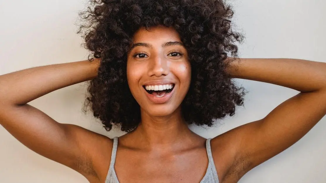 Cheerful African American woman with curly hair, representing the best cosmetic dentist near me.