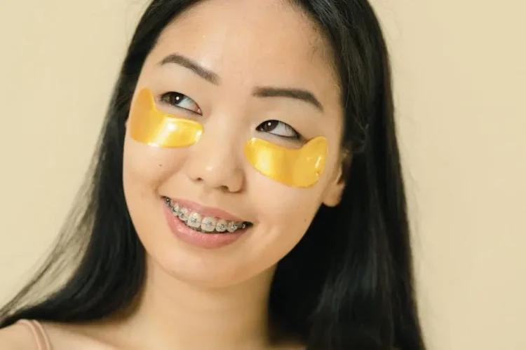 Smiling woman with braces and under-eye patches, showcasing braces benefits.