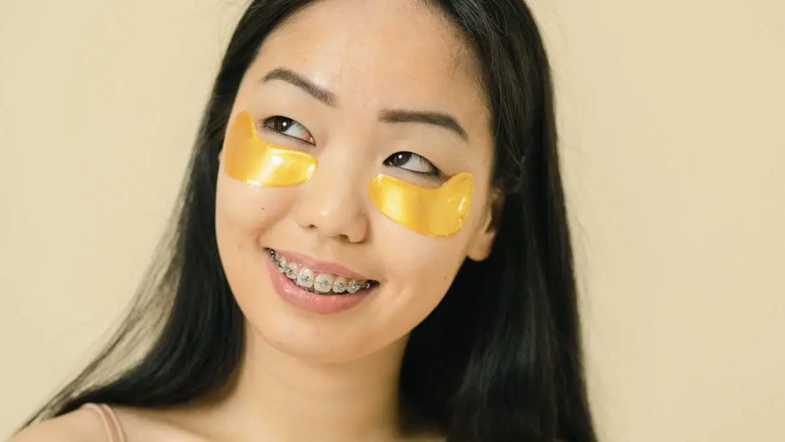 Smiling woman with braces and under-eye patches, showcasing braces benefits.