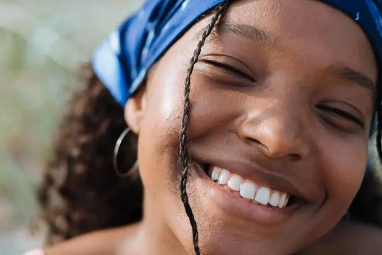 Girl wearing braces with colorful bands and a bandana, smiling.