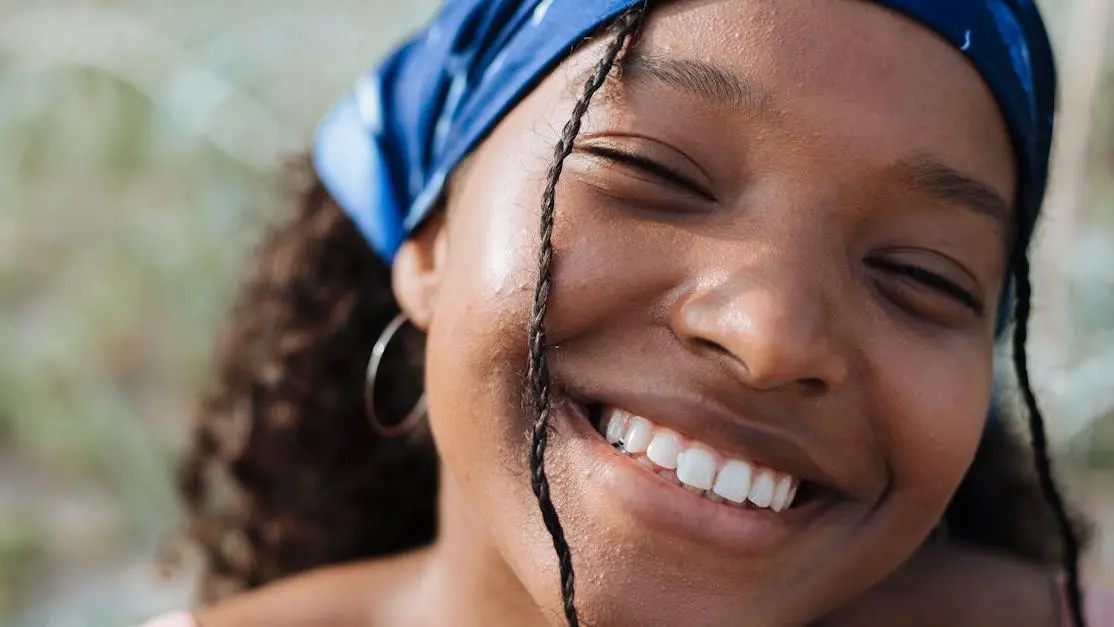 Girl wearing braces with colorful bands and a bandana, smiling.