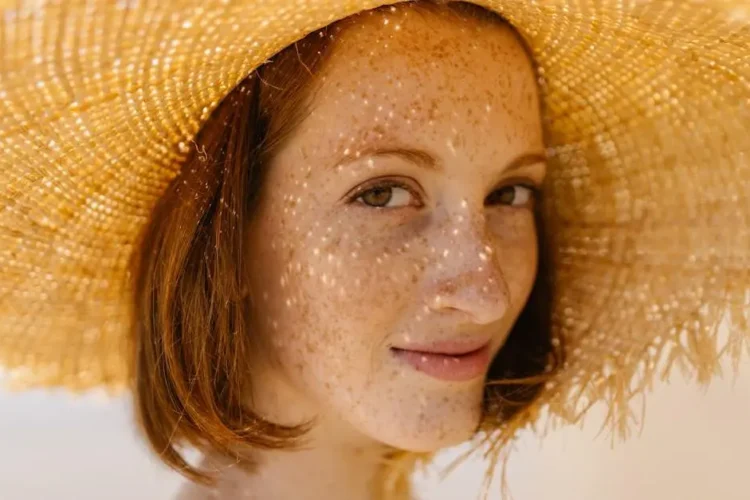 Smiling woman outdoors with straw hat, highlighting healthy front teeth.