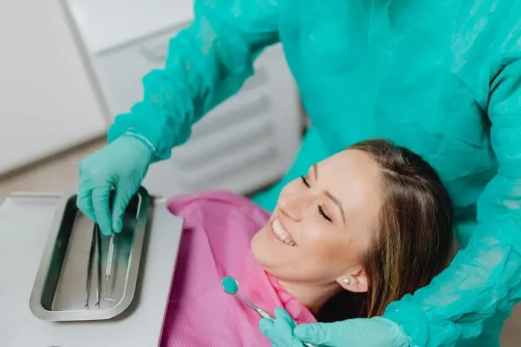 Smiling woman in dental chair, dentist preparing instruments, Cosmetic dentistry services in Cookstown.