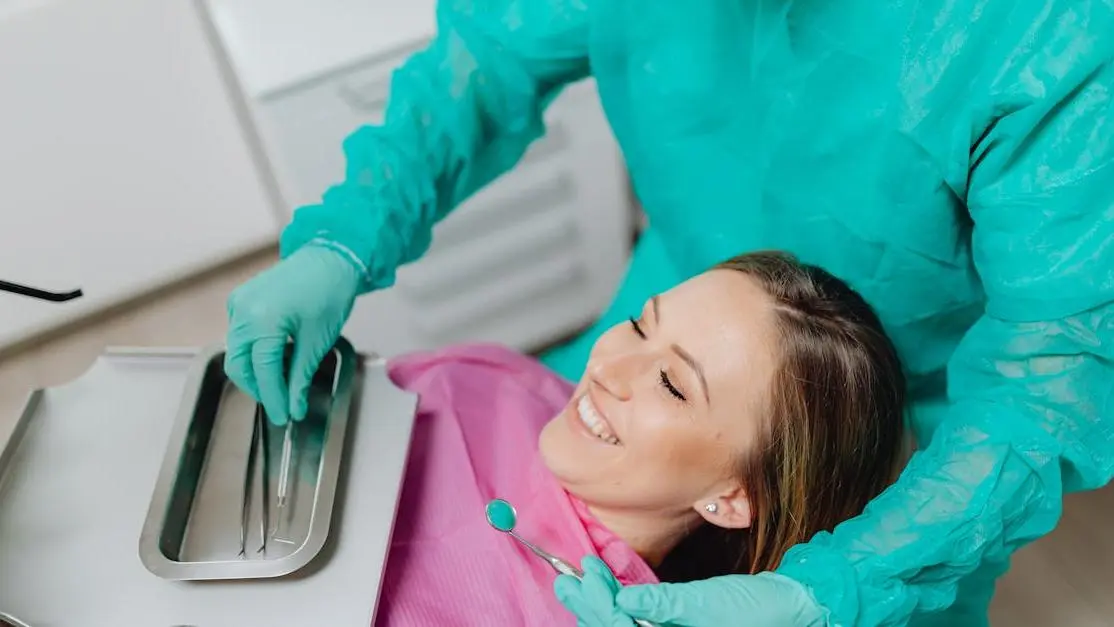 Smiling woman in dental chair, dentist preparing instruments, Cosmetic dentistry services in Cookstown.