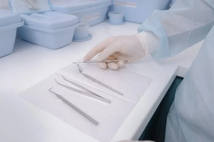 Dental tools on table, dentist in gloves, exemplifying dental infection control in a clean environment.