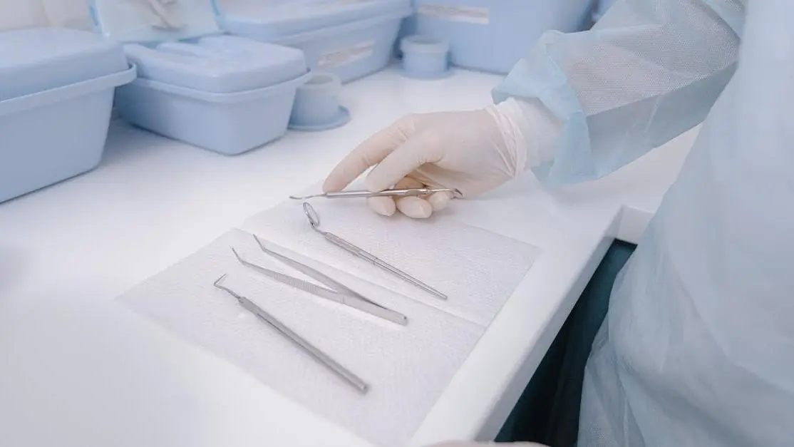 Dental tools on table, dentist in gloves, exemplifying dental infection control in a clean environment.