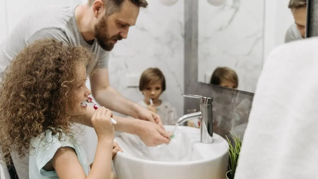 Father and children brushing teeth in bathroom, promoting family dental care for children and adults.