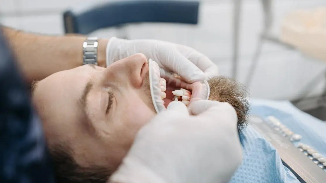 Dentist matching teeth color with shade guide to fix cracked tooth.