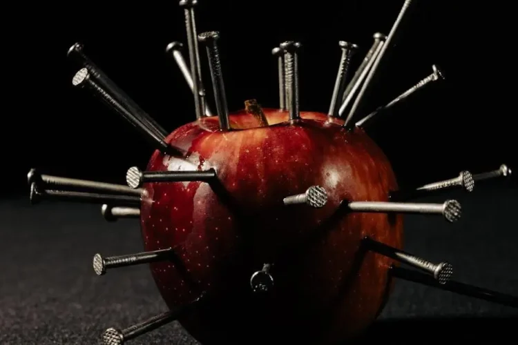 Red apple with nails, showcasing foods to avoid with braces.