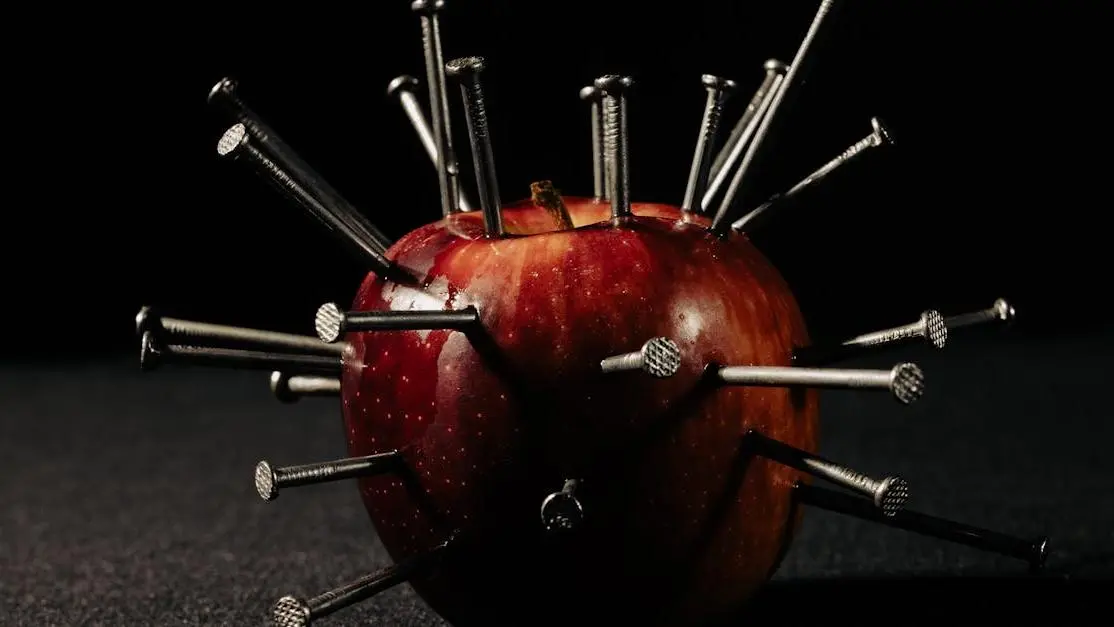 Red apple with nails, showcasing foods to avoid with braces.