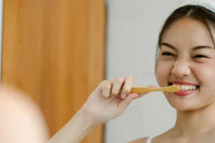 Smiling woman with a toothbrush, promoting general dental care tips.