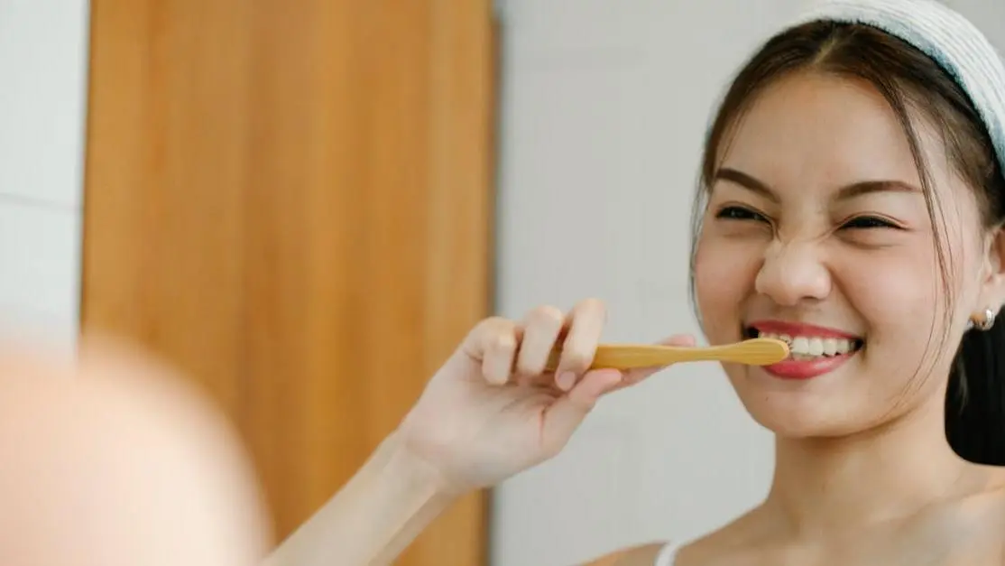 Smiling woman with a toothbrush, promoting general dental care tips.