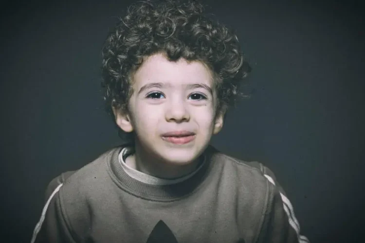 Smiling child with curly hair, representing general dentistry in a studio setting.