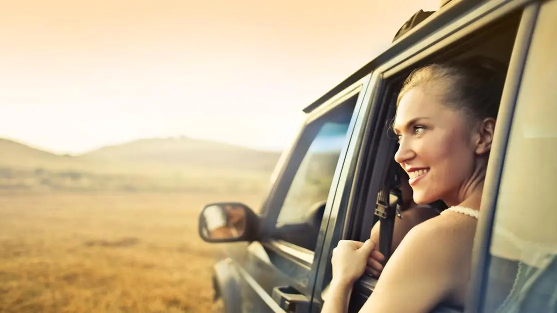 Young woman showing a gummy smile while enjoying a sunset through an open car window.