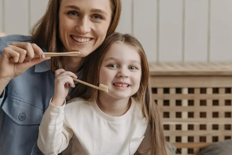 Smiling woman and child holding toothbrush; linked to heart disease and oral health