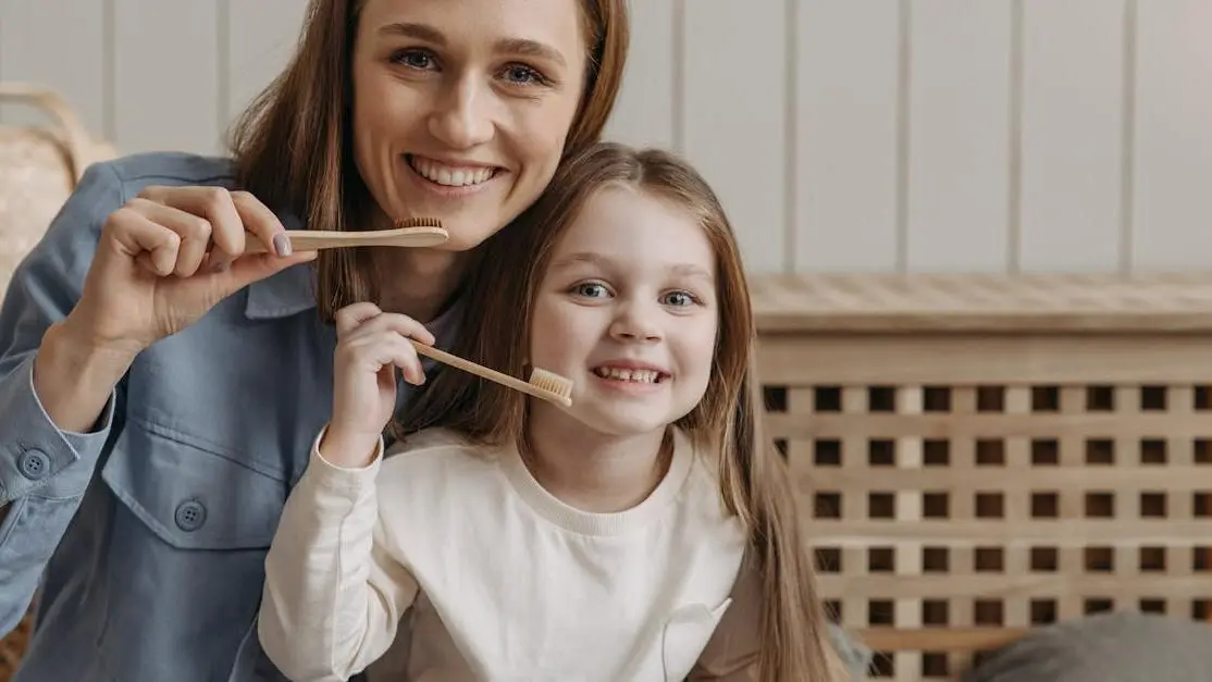 Smiling woman and child holding toothbrush; linked to heart disease and oral health