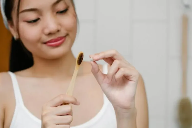 Asian woman with bamboo toothbrush, illustrating "How often should you clean your teeth?"