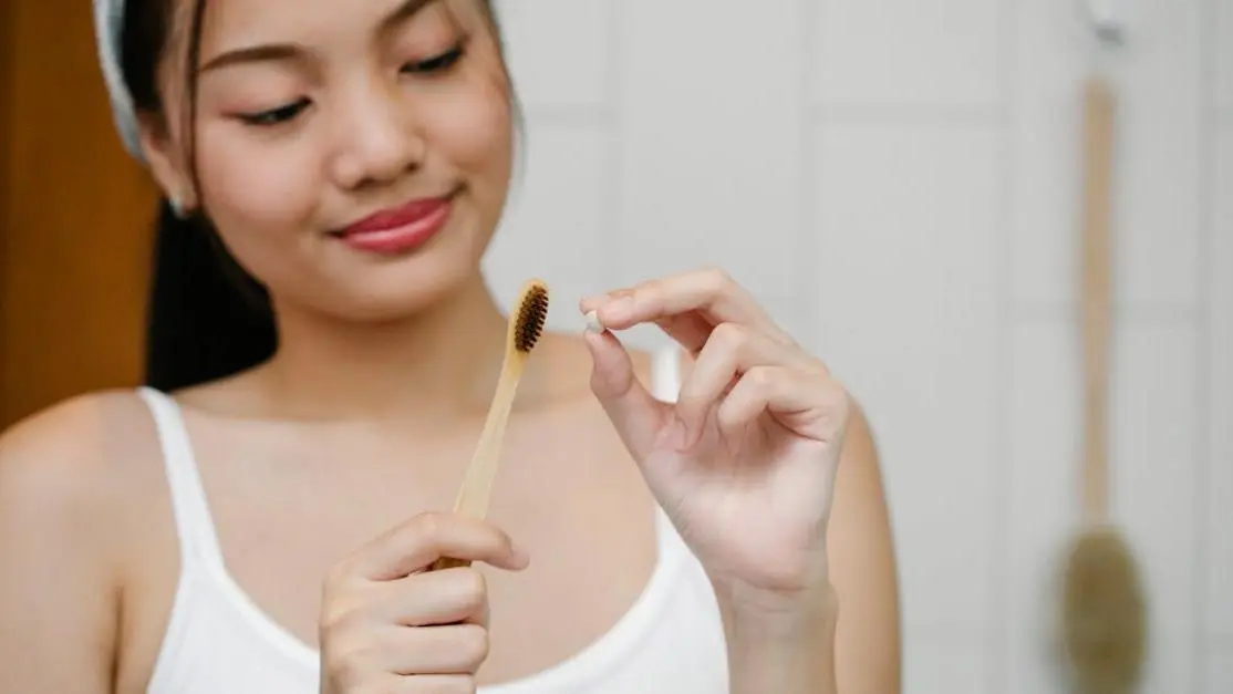 Asian woman with bamboo toothbrush, illustrating "How often should you clean your teeth?"