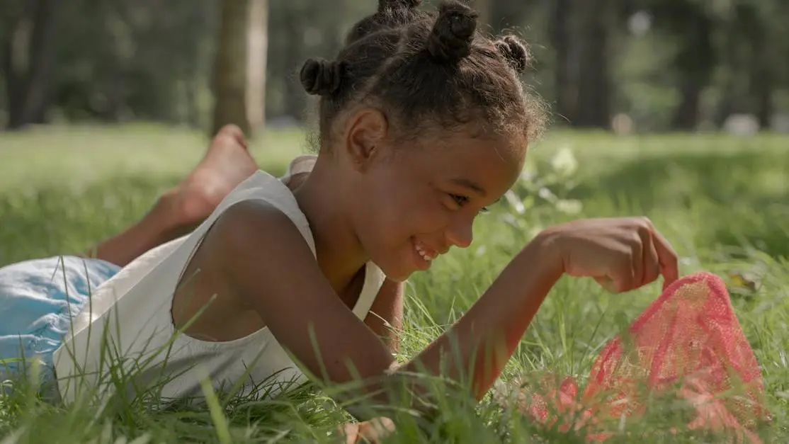 Young girl smiling in a sunny park, highlighting the importance of dental care for kids.