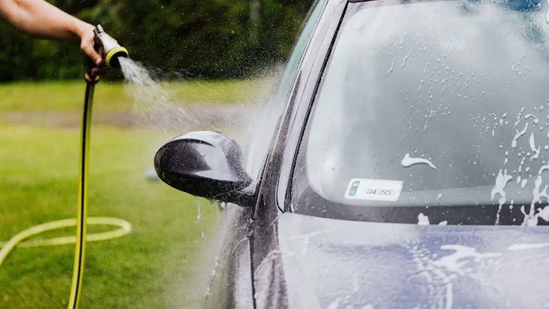 Regular cleaning of a car with a hose, highlighting the importance of regular cleanings.