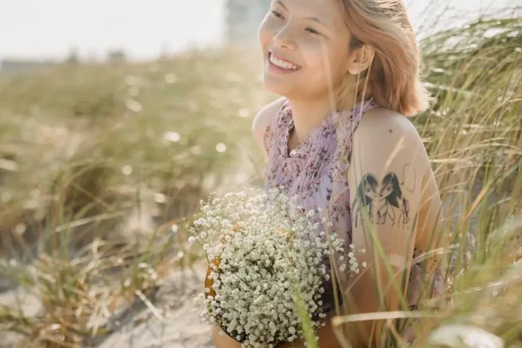 Smiling woman practicing Invisalign teeth care while holding flowers