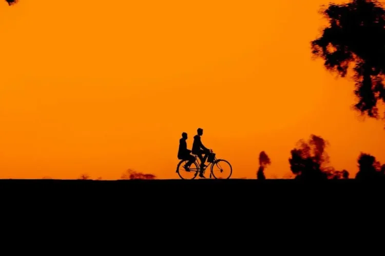 Silhouettes of cyclists at sunset, symbolizing life with missing all your teeth.