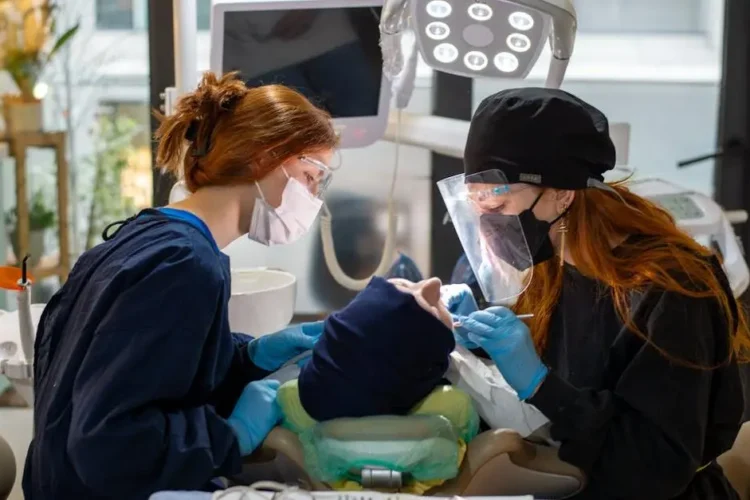 Dentist performing oral and maxillofacial surgery with assistant in a dental clinic