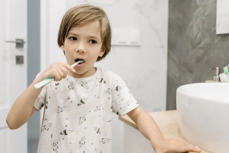 Young boy brushing teeth, promoting oral health education.