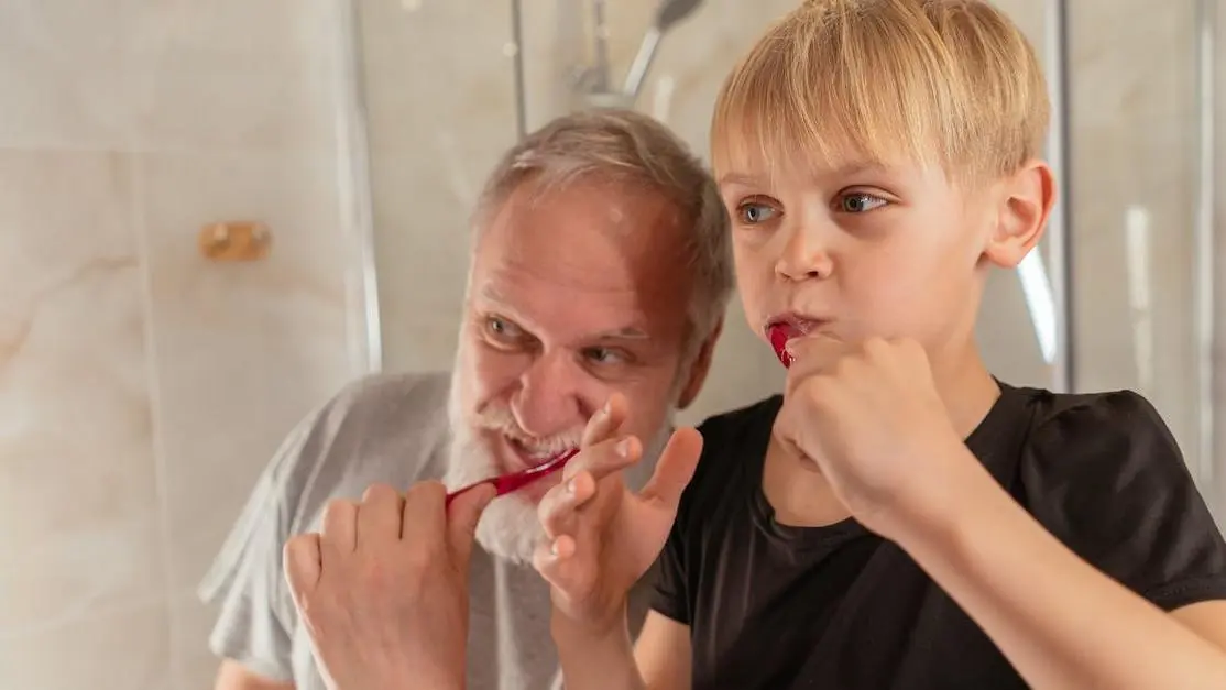 Grandfather teaches grandson dental hygiene, showcasing oral health tips for kids and adults.