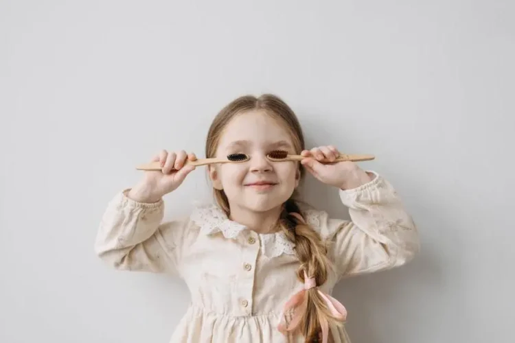 Child playfully holding toothbrushes, representing pediatric dental care tips.