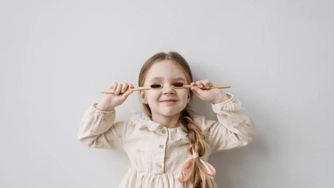 Child playfully holding toothbrushes, representing pediatric dental care tips.