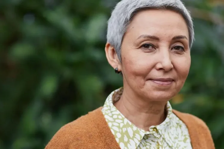 Joyful senior Asian woman outdoors, symbolizing confidence with permanent dentures.